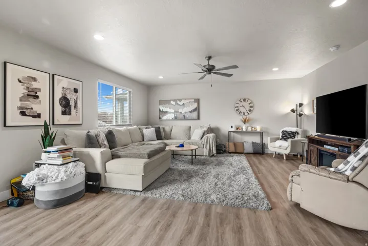 Spacious living area featuring wood-finish flooring, recessed lighting, and a ceiling fan