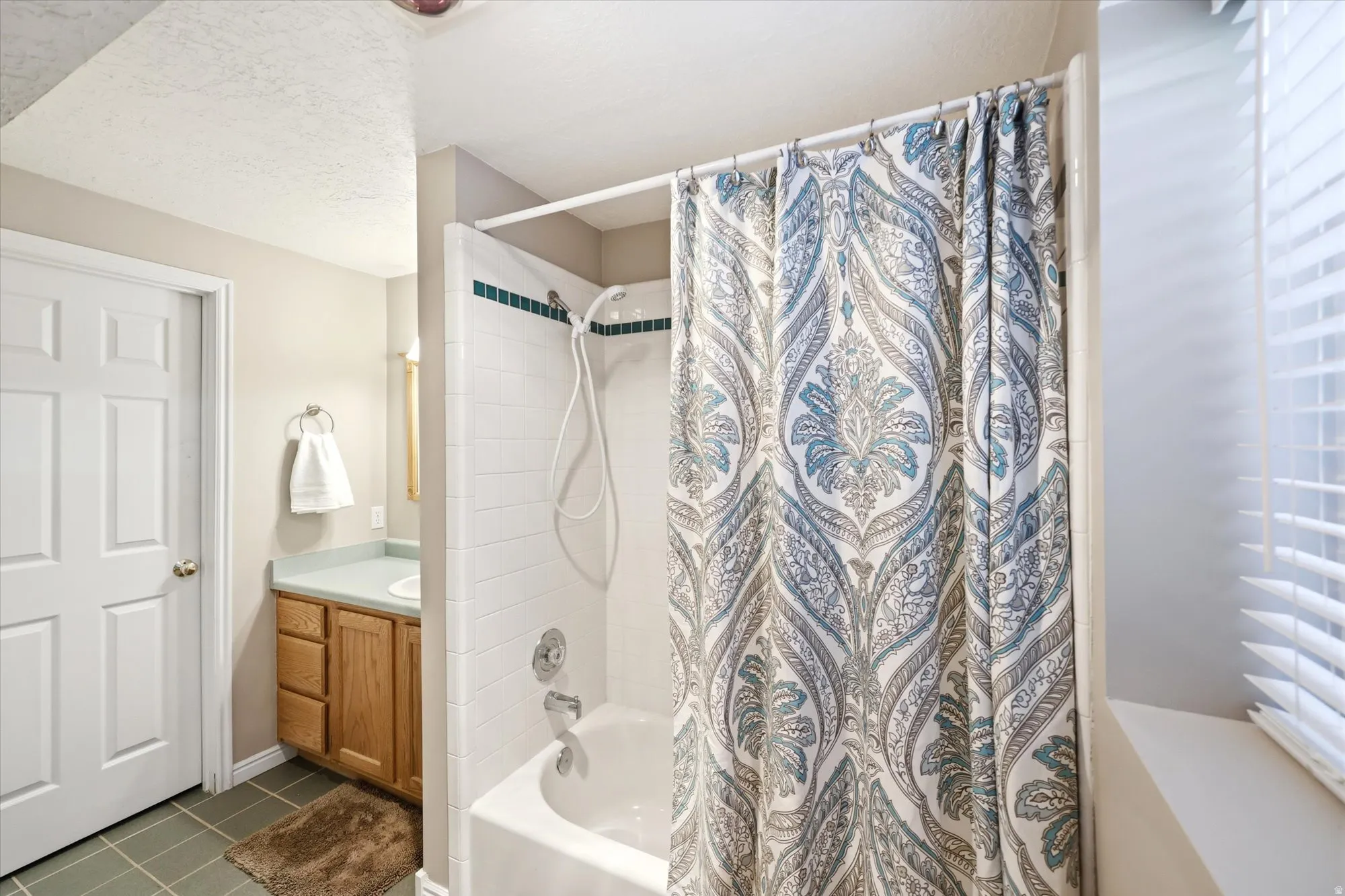 Bathtub and shower combination featuring white subway tile surround with decorative accent band