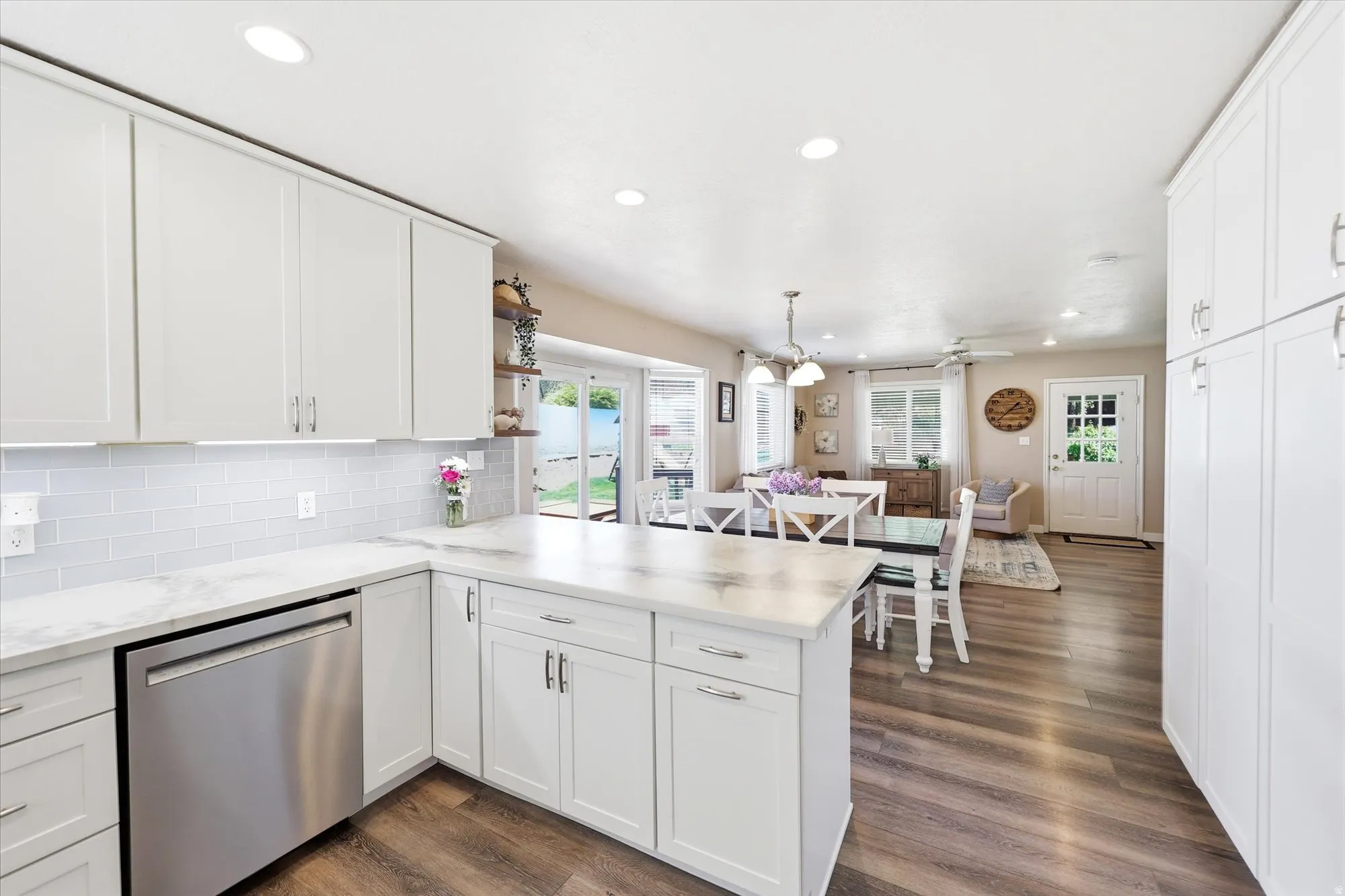 Kitchen featuring white shaker cabinetry, light-toned countertops, a subway tile backsplash, stainless steel appliances, and recessed lighting