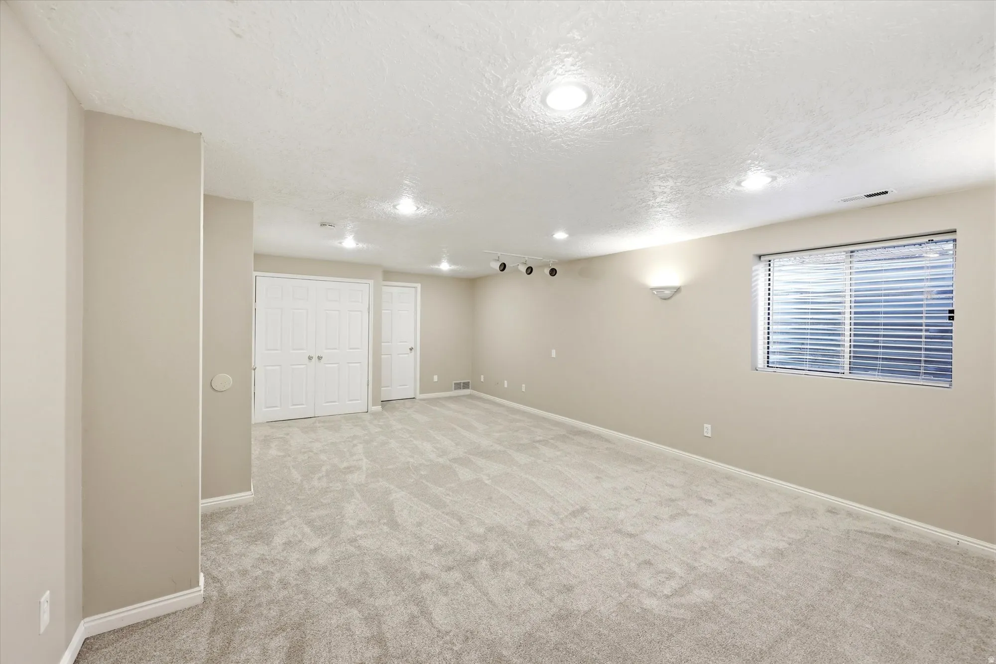 Spacious room with light-colored carpeting, neutral painted walls, and white trim