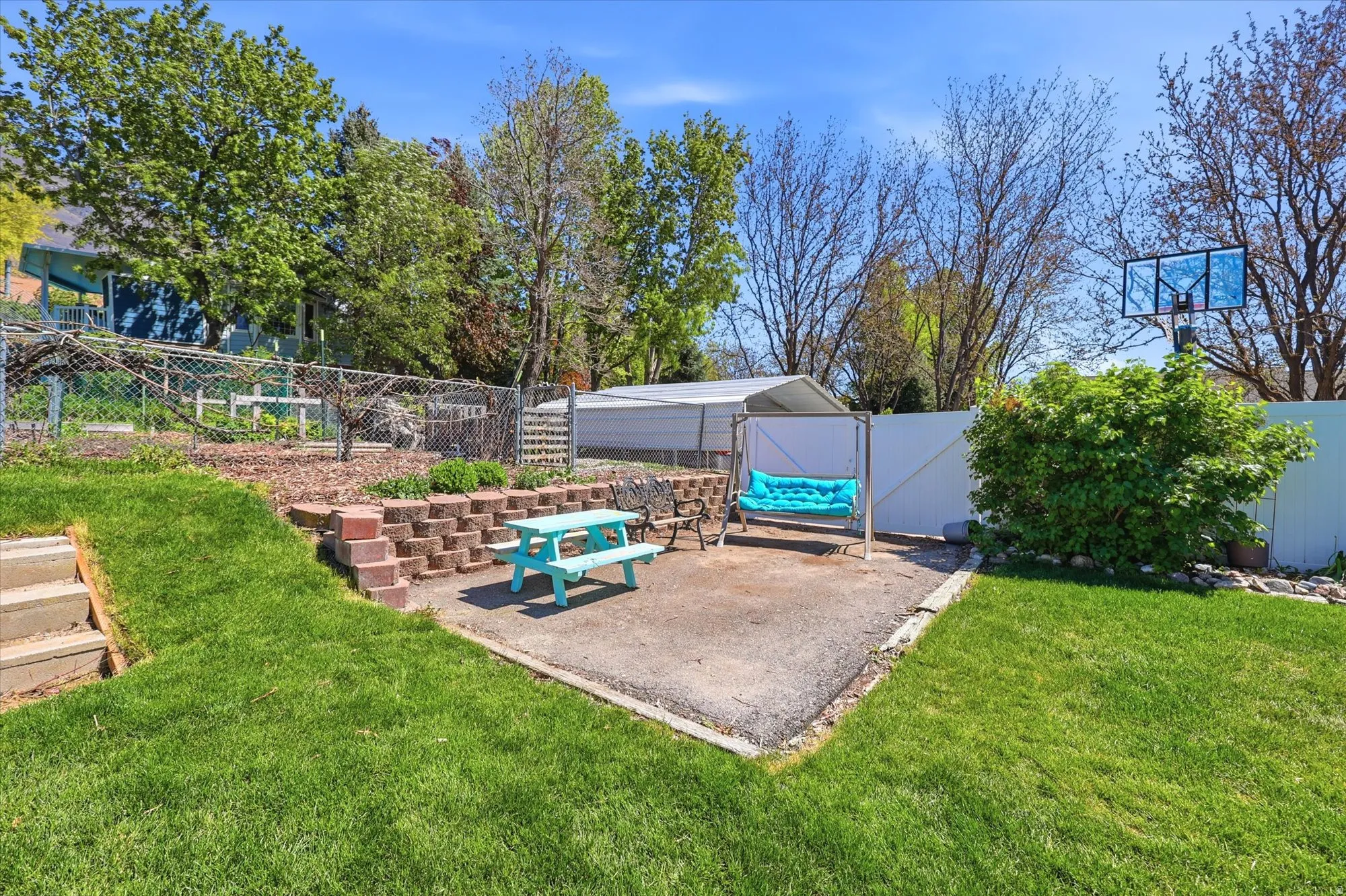 Expansive backyard featuring a concrete patio, a tiered retaining wall with red brick-like pavers, and a manicured lawn