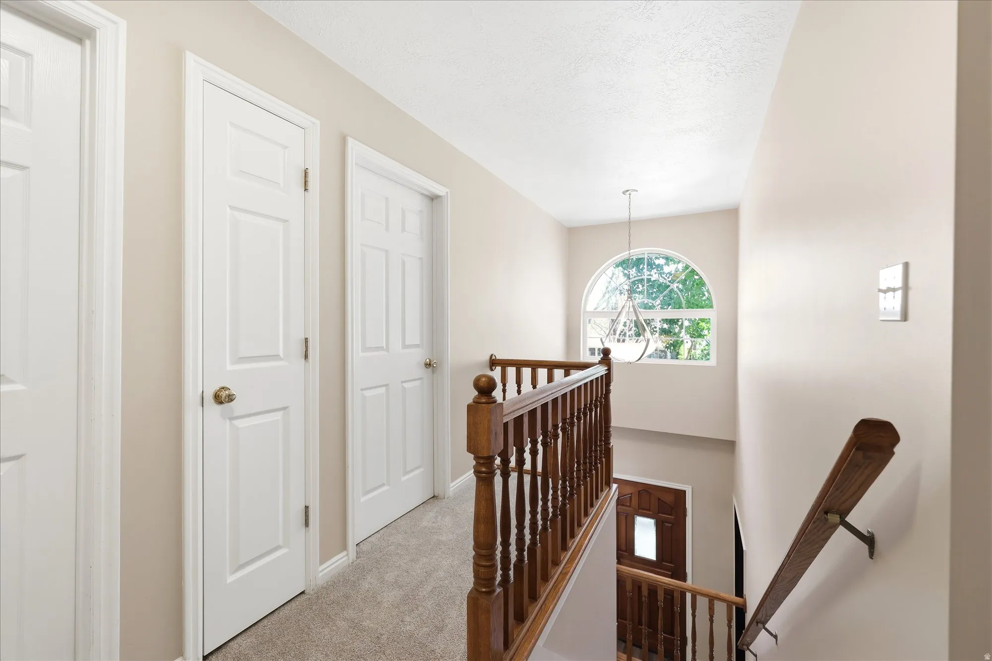 Upper-level hallway featuring neutral wall tones, white paneled doors, and carpeted flooring