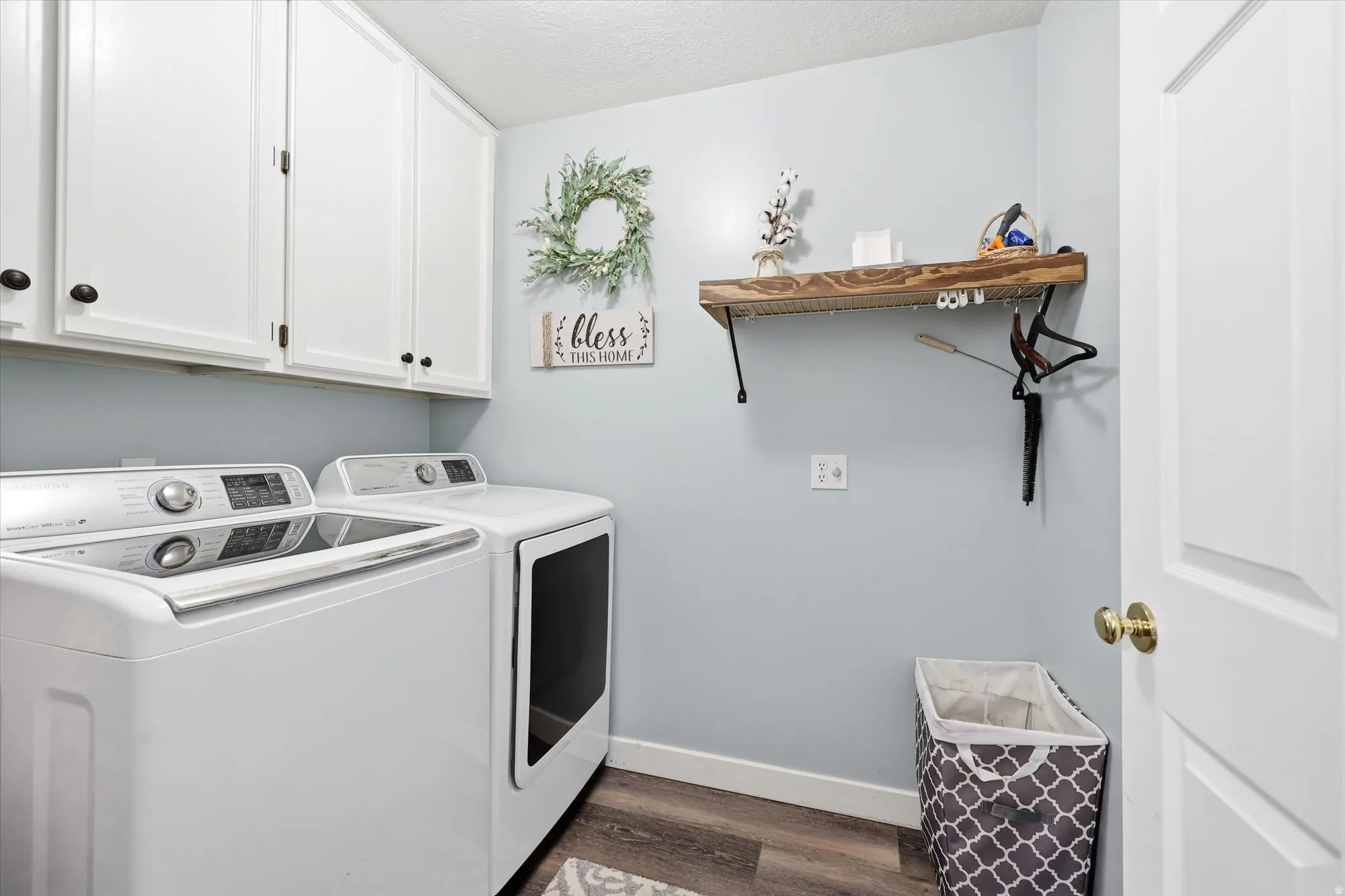 Practical laundry space featuring white shaker-style cabinetry with dark hardware