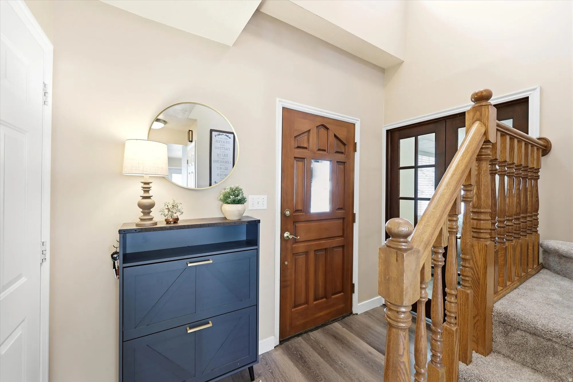 Foyer featuring wood-finish flooring and a natural wood staircase with balusters