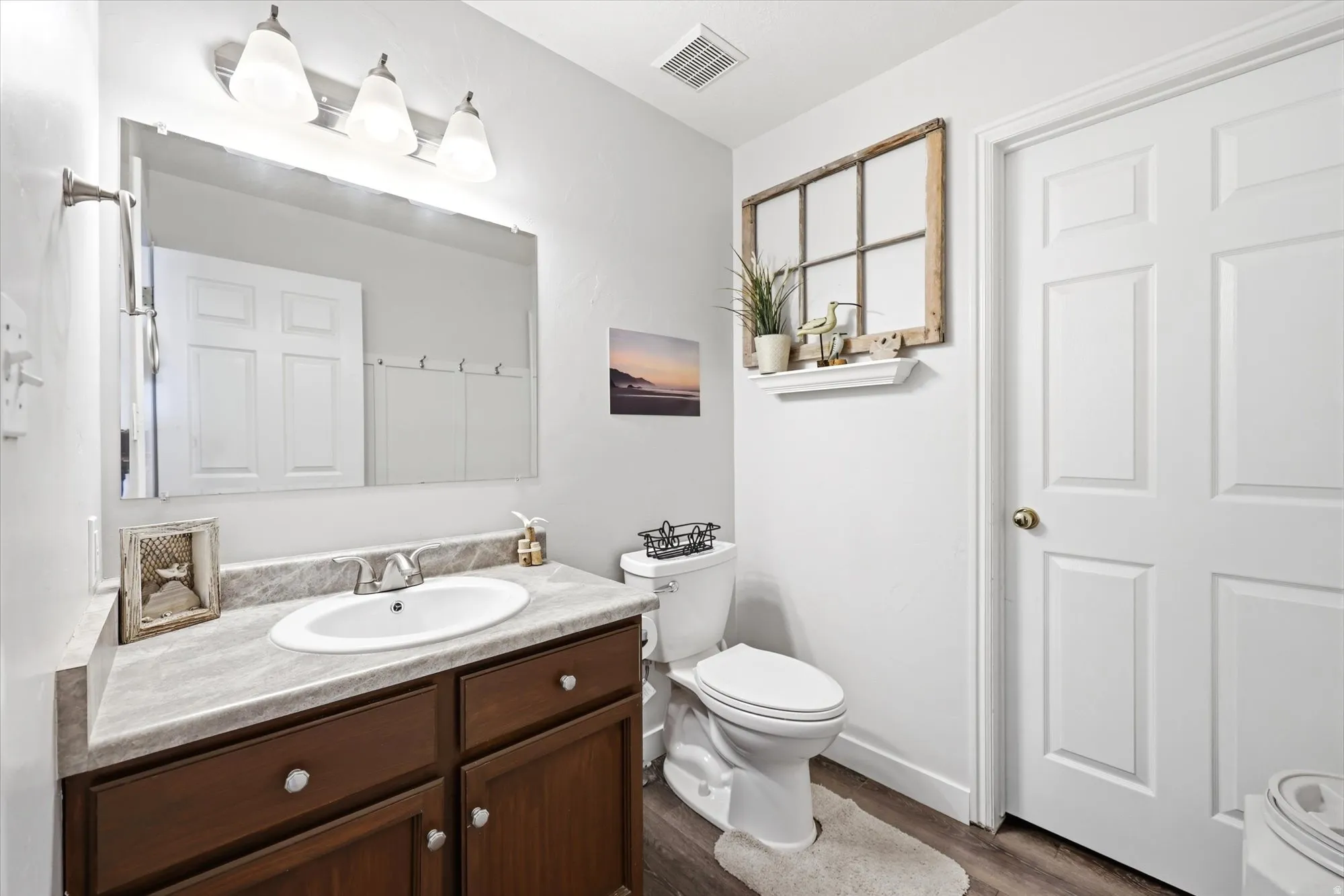 Bathroom featuring a dark wood-finish vanity with a single basin sink, laminate countertop, and a chrome faucet