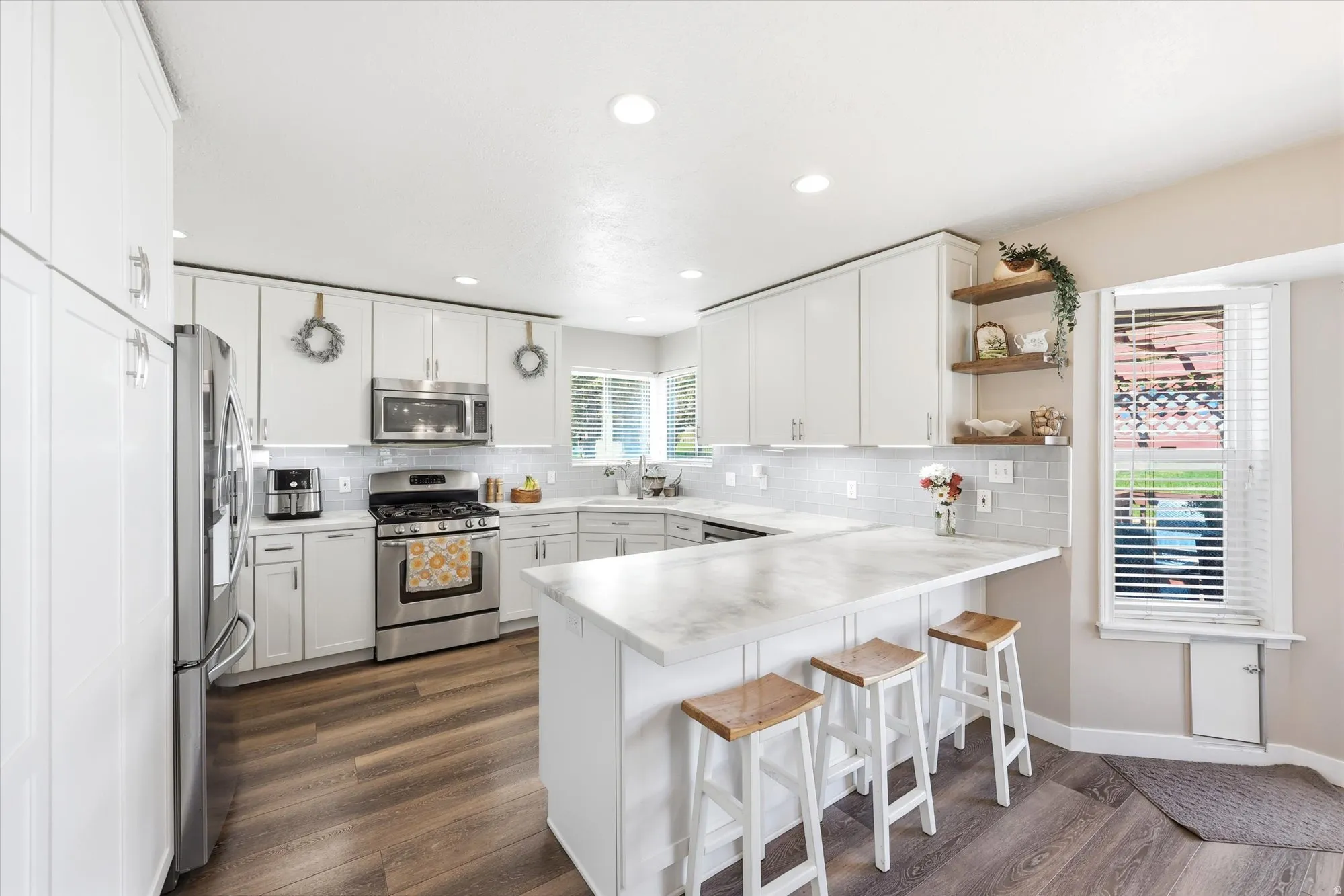 Spacious kitchen featuring white cabinetry, light-toned countertops, and wood-finish flooring