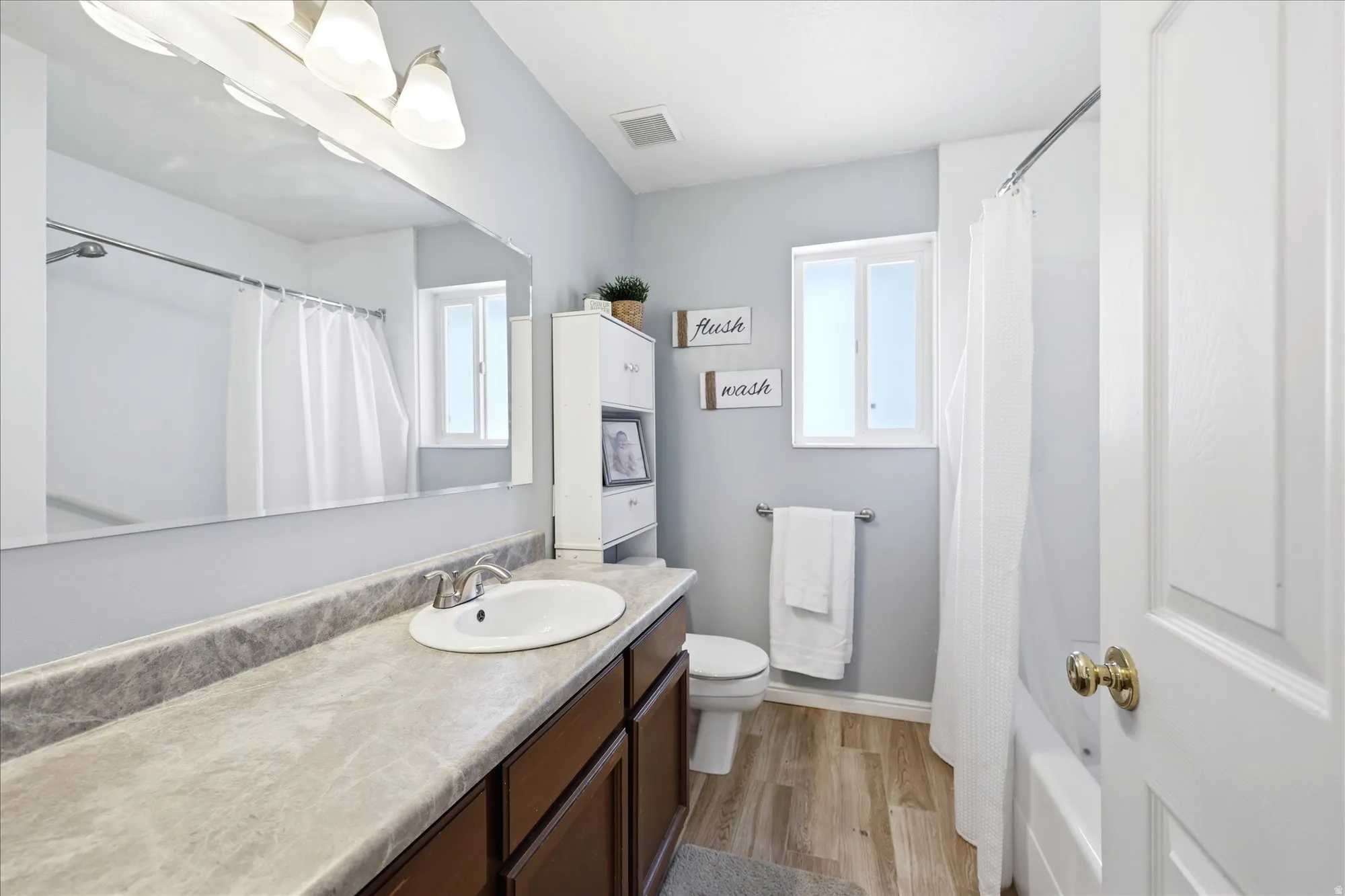 Bathroom featuring a vanity with dark wood-finish cabinetry, a large integrated sink, and a stone-look countertop