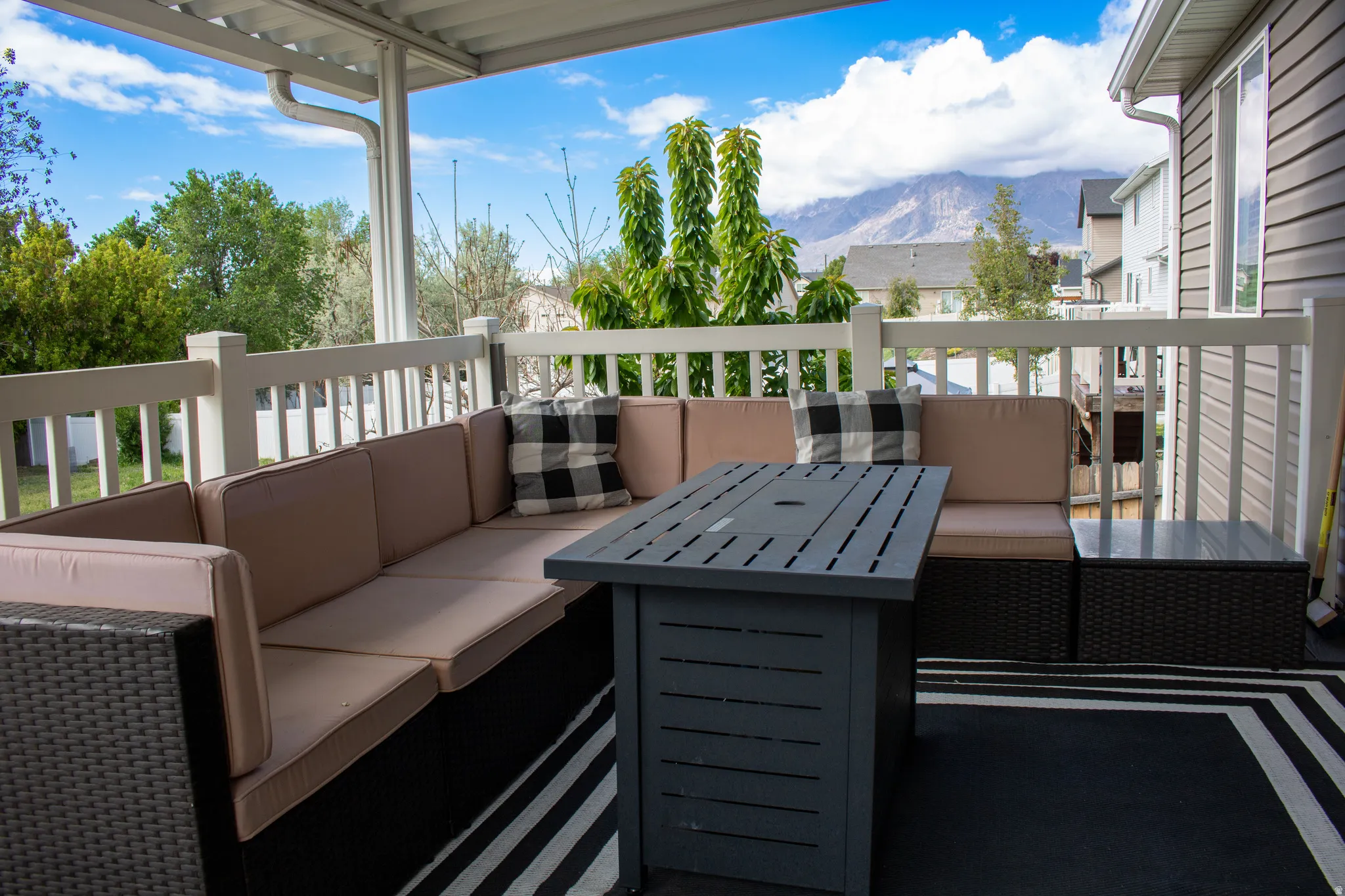 Covered outdoor deck featuring white railings and a mountain backdrop