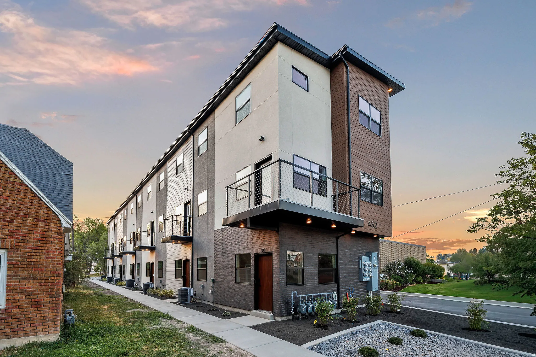 Modern multi-story facade featuring varied siding materials, including wood-look panels and smooth stucco