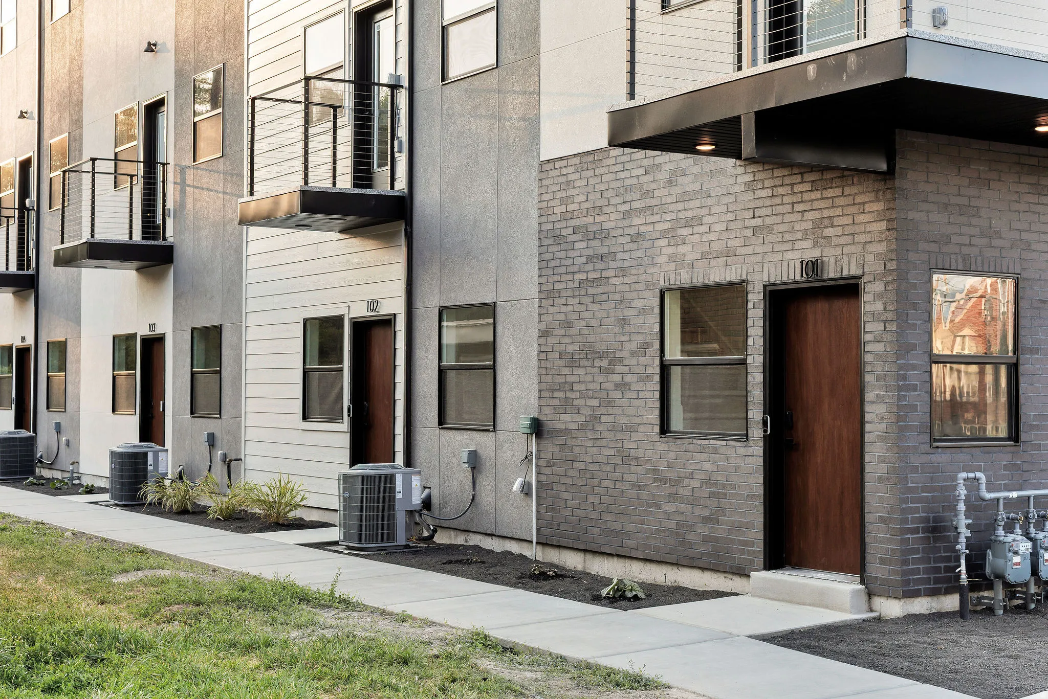 Modern multi-unit residential complex featuring clean-lined architecture with mixed material facades of brick and fiber cement siding