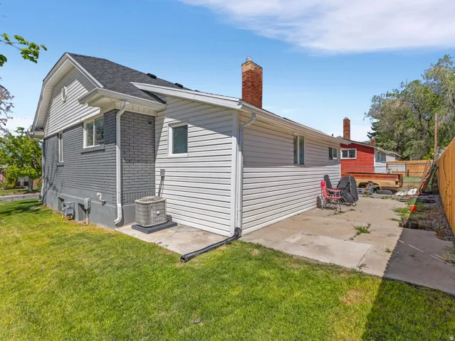 Side exterior showcasing grey brick and white siding, with a concrete patio