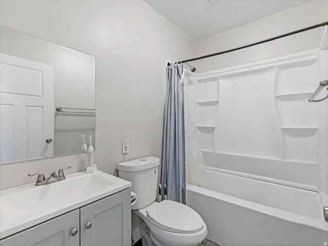 Bathroom featuring a white integrated sink vanity with gray cabinetry, brushed nickel faucet, large wall-mounted mirror, and a white bathtub with a shower surround