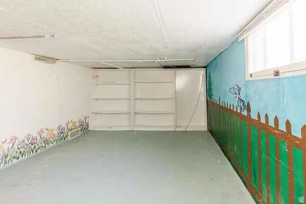 Room with built-in shelving, a single window, and a painted mural wall