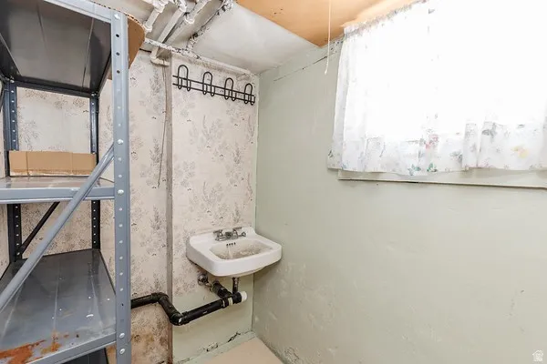 Utility sink with dual-handle faucet and exposed plumbing