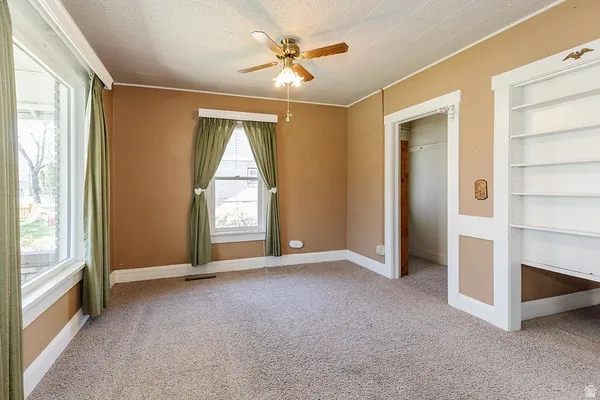 Carpeted interior space featuring warm-toned walls, white trim, and a ceiling fan with light fixture