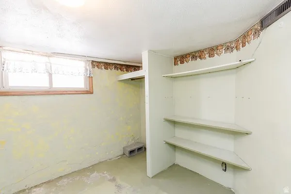 Room featuring a single-pane window, built-in shelving, a wall-mounted light fixture, and a ceiling light