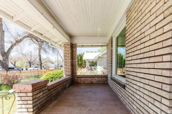 Inviting covered front porch with brick half-walls, a wood-finish floor, and a beadboard ceiling