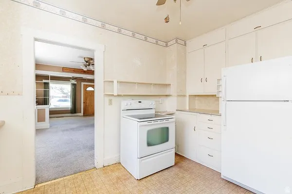 Kitchen featuring white cabinetry, white appliances, and patterned vinyl flooring