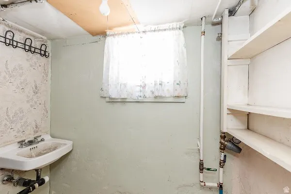 Utility room featuring a wall-mounted sink, built-in shelving, and a window with natural light