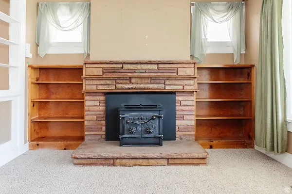 Central stone fireplace with a cast-iron wood-burning stove, flanked by built-in wood shelving units