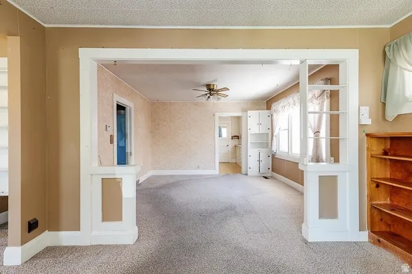 Expansive room featuring light-colored carpeting, a ceiling fan, and built-in shelving