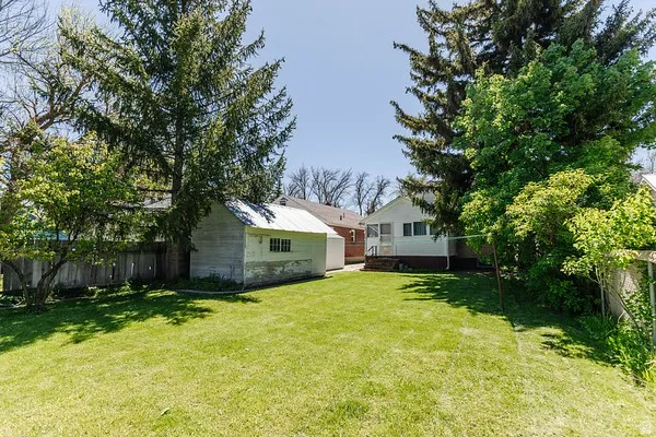 Expansive lawn area with a detached outbuilding featuring a metal roof