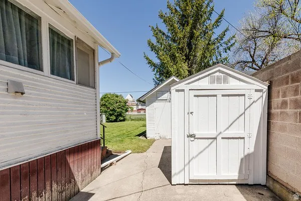 White storage shed featuring double doors and a gable roof with vents