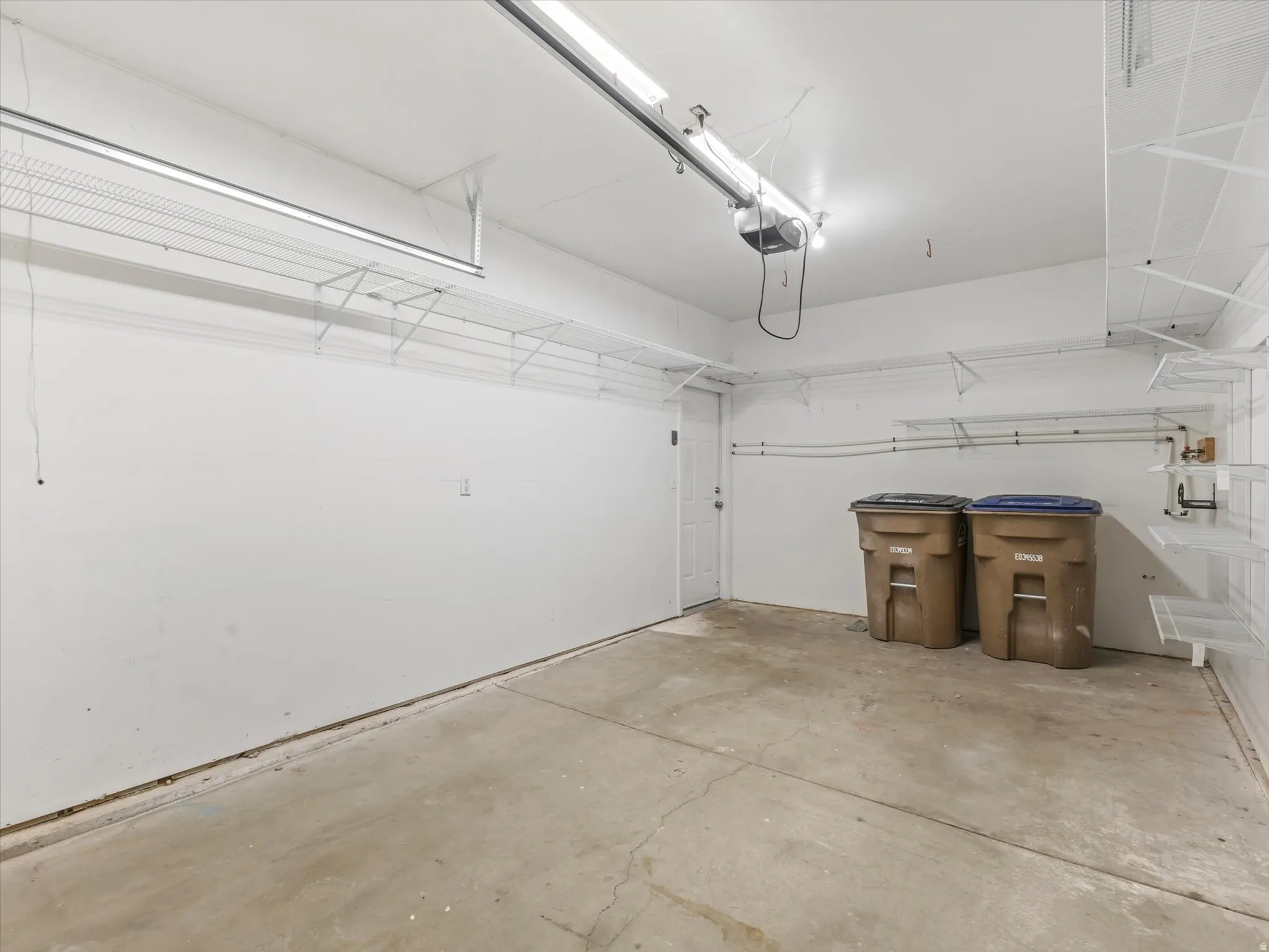 Finished garage interior featuring concrete flooring, white painted walls, and overhead lighting