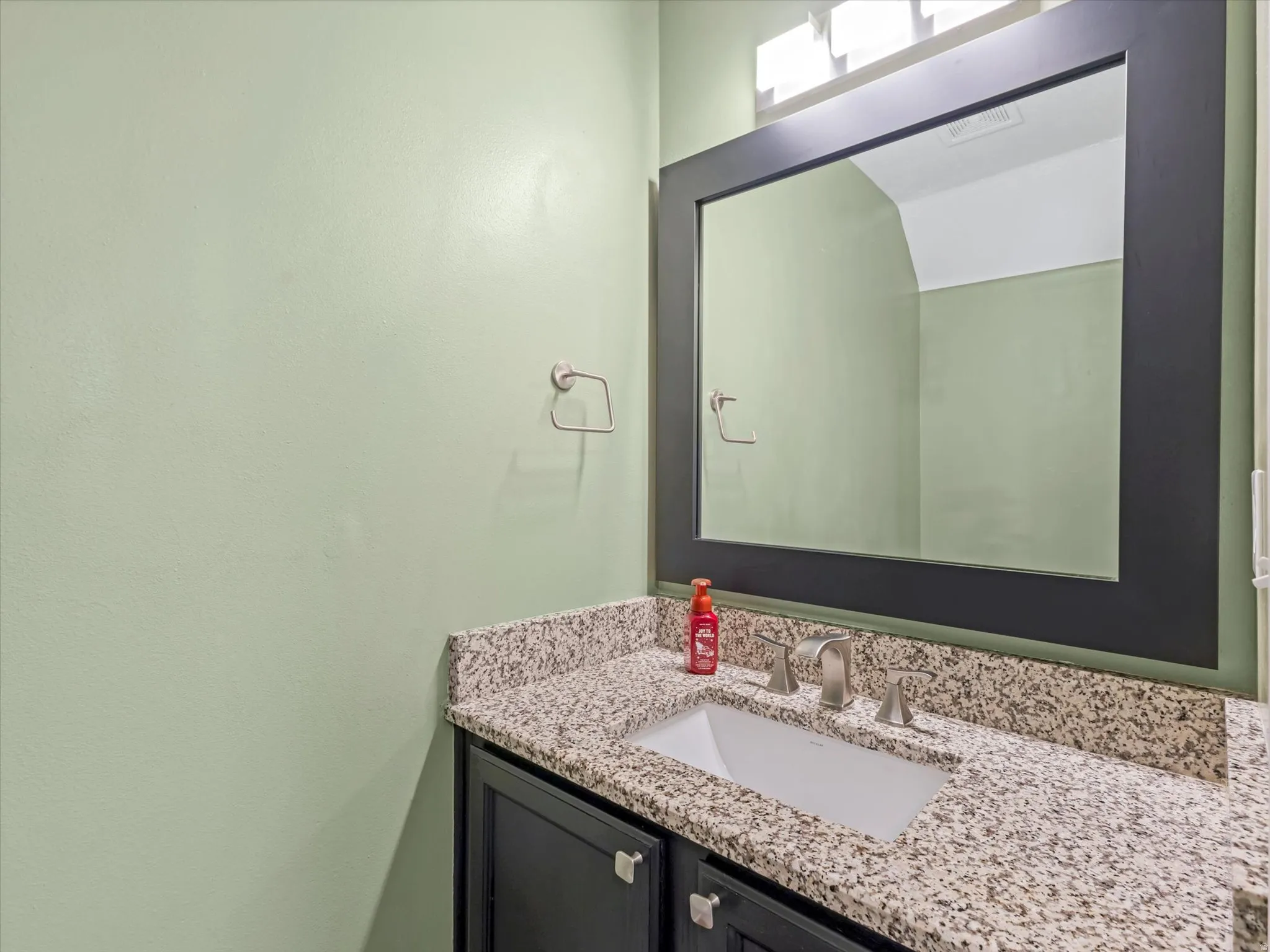 Bathroom vanity featuring a speckled countertop, undermount sink, and brushed nickel faucet