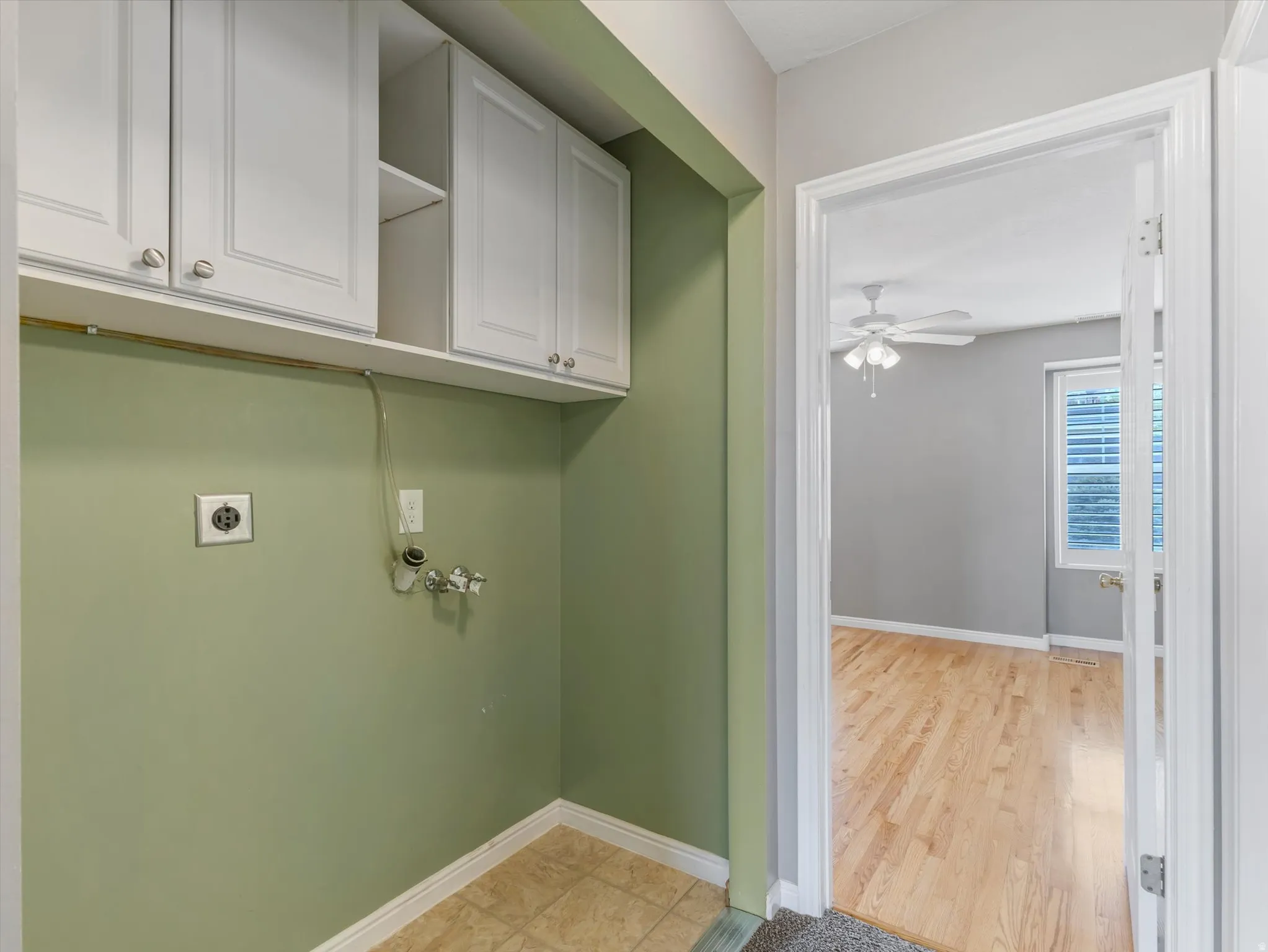 Dedicated laundry area featuring upper white cabinetry, tile flooring, and a utility hookup