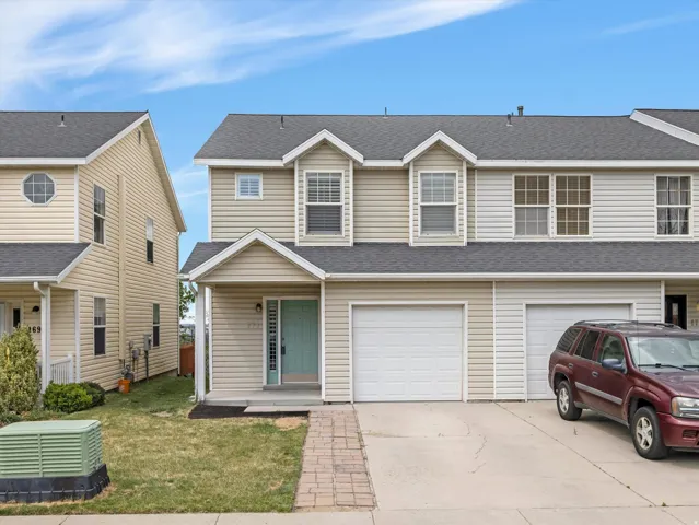 Two-story townhome with light-toned siding and a dark shingle roof