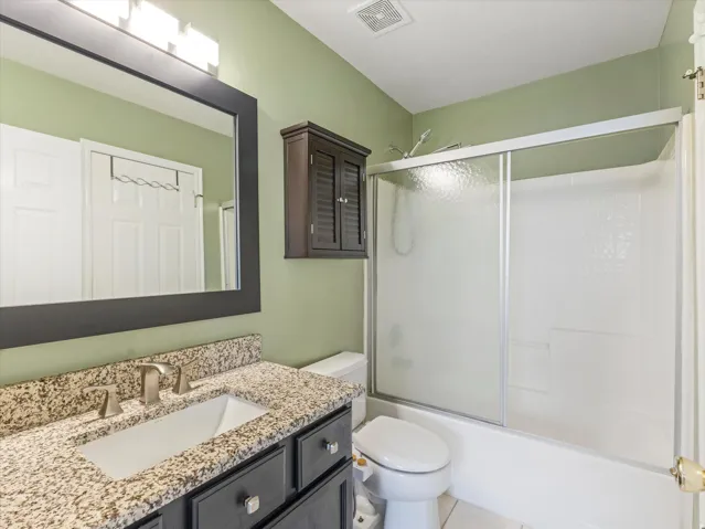 Bathroom featuring a vanity with a granite-style countertop, undermount sink, and brushed nickel faucet