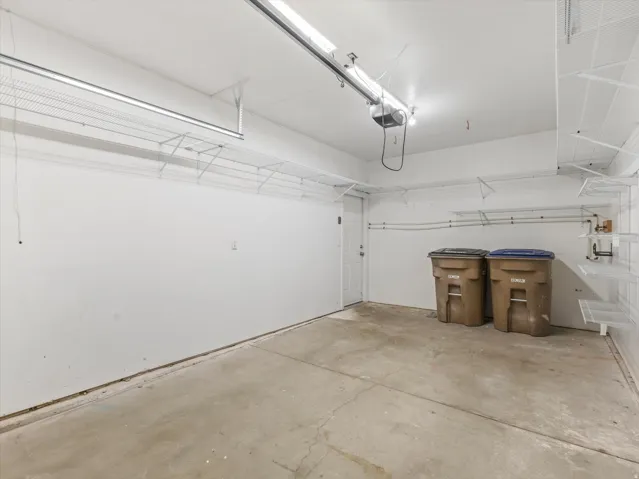 Finished garage interior featuring concrete flooring, white painted walls, and overhead lighting