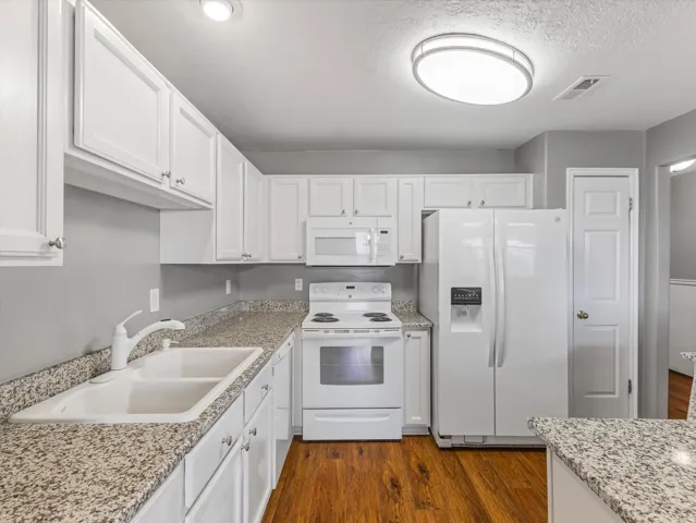 Kitchen featuring white cabinetry, granite-finish countertops, and wood-finish flooring