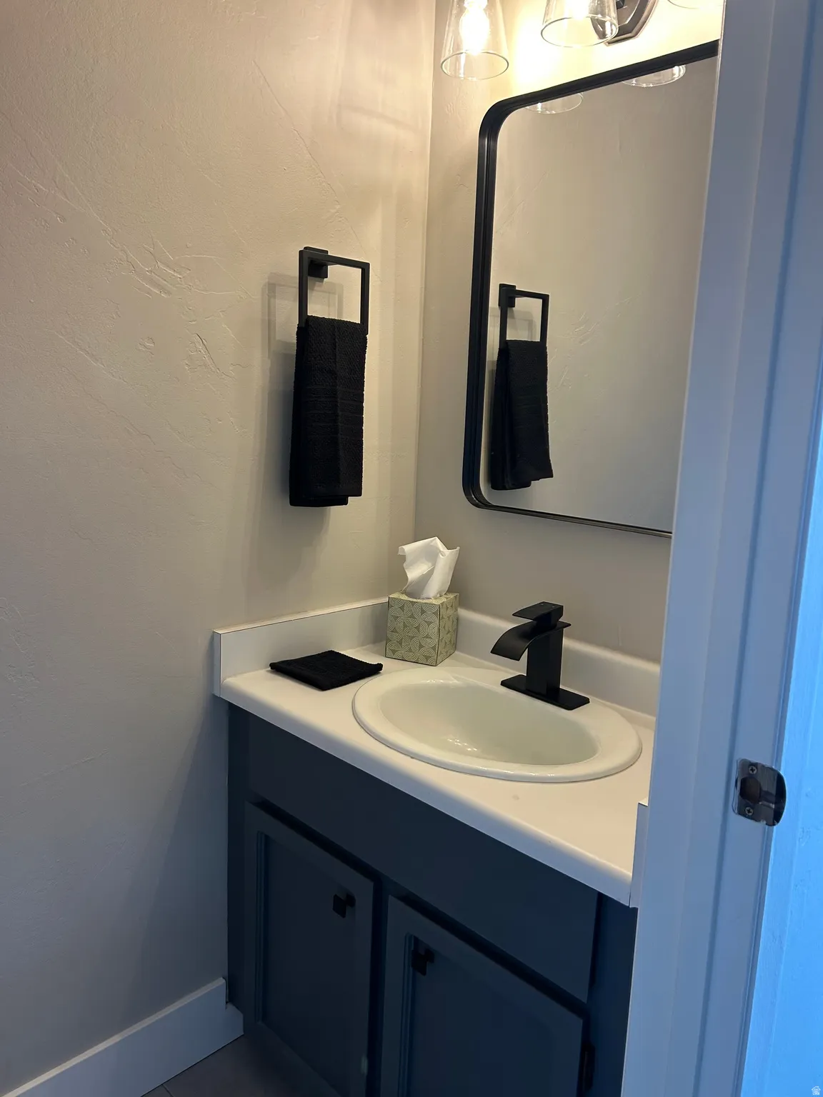 Vanity with a white countertop and integrated sink, matte black faucet, and painted base cabinetry