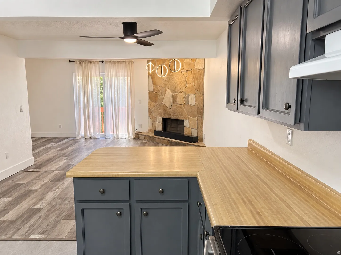 Wood-finish countertops, dark cabinetry, and wood-finish flooring