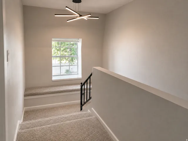 Staircase featuring carpeted steps, a window seat, and a modern linear chandelier