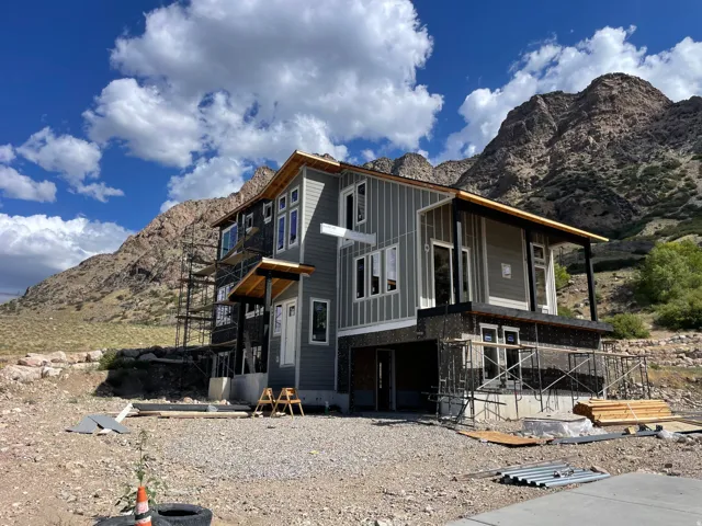 Modern multi-level exterior with board and batten siding, multiple balconies, and a mountain backdrop