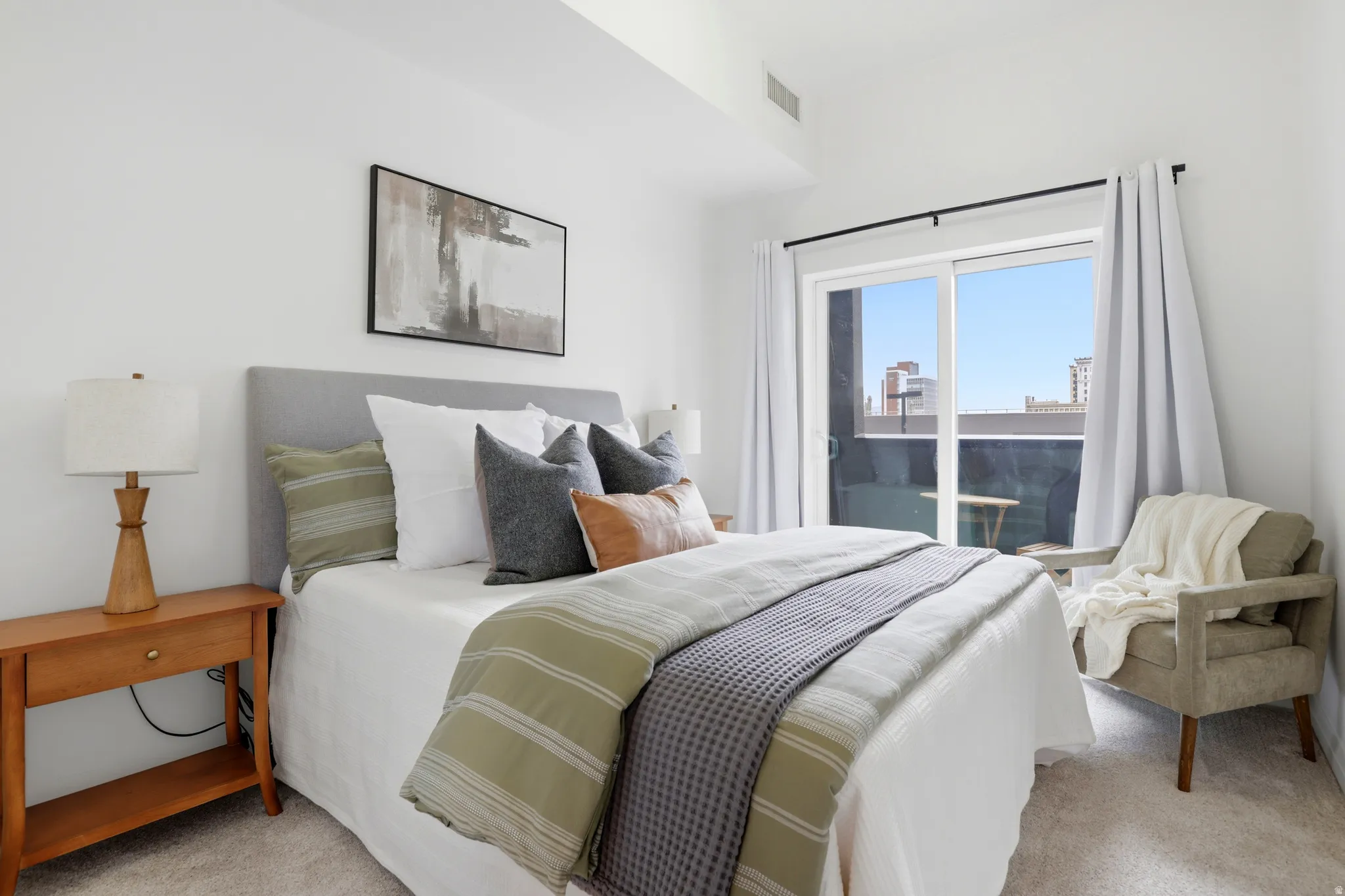 Bedroom featuring white walls, light-colored carpeting, a sliding glass door leading to an outdoor space, and a built-in recessed light fixture