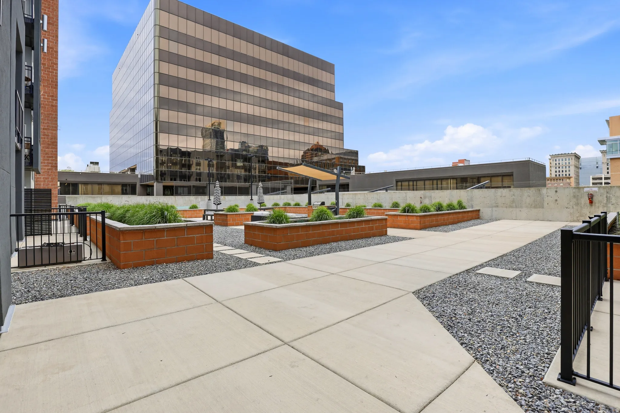 Rooftop patio with concrete pavers, gravel accents, brick planter boxes, and black metal railings