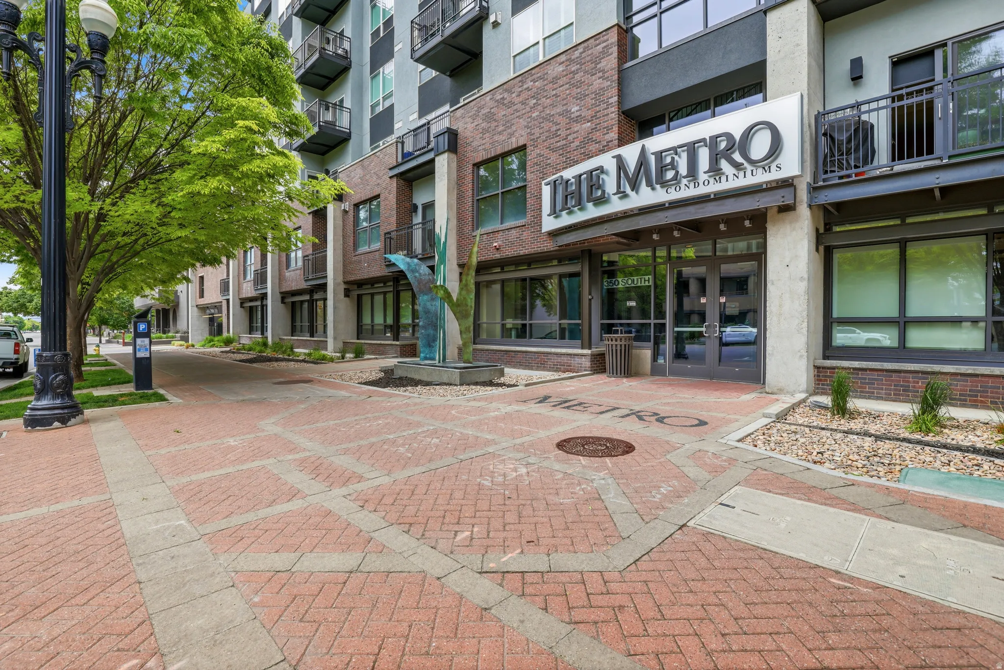 Modern brick and concrete facade featuring a prominent "The Metro Condominiums" sign, a welcoming glass entry, and decorative metal balconies