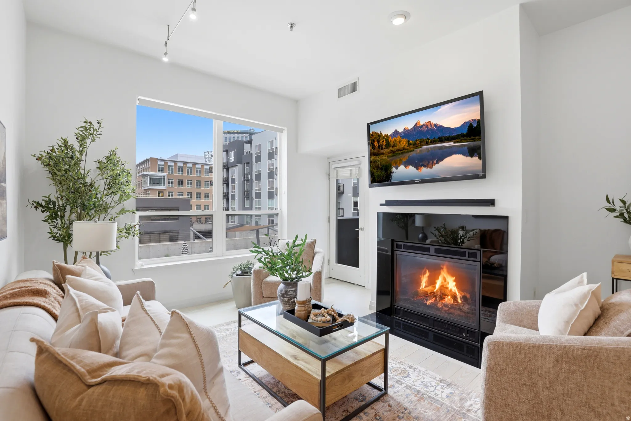 Living area featuring a floor-to-ceiling window, light-toned walls, and wood-finish flooring