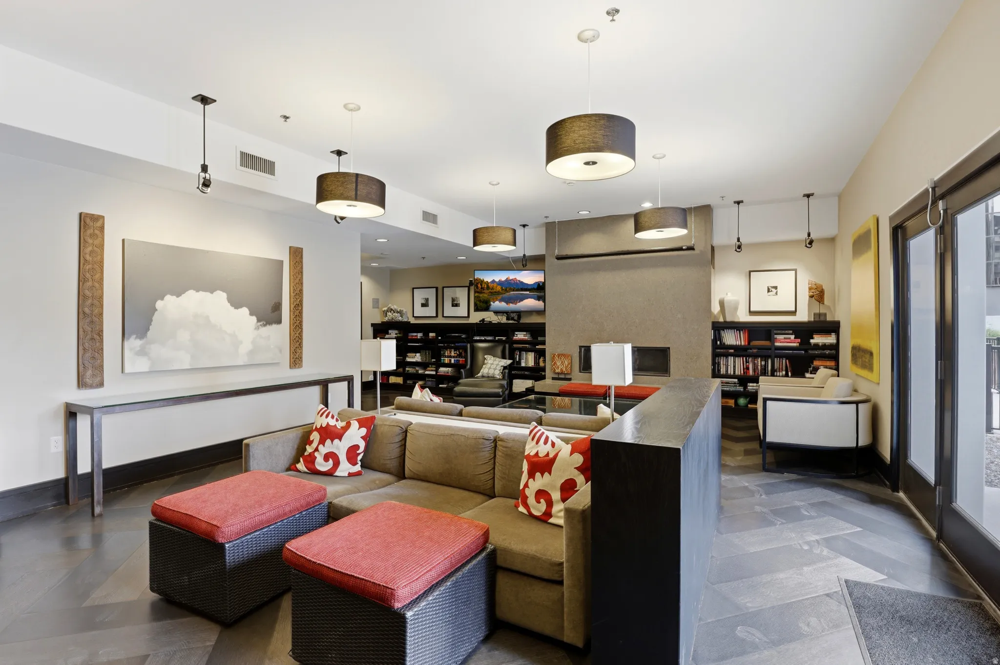 Spacious common area featuring herringbone pattern flooring, multiple drum pendant lights, and built-in shelving