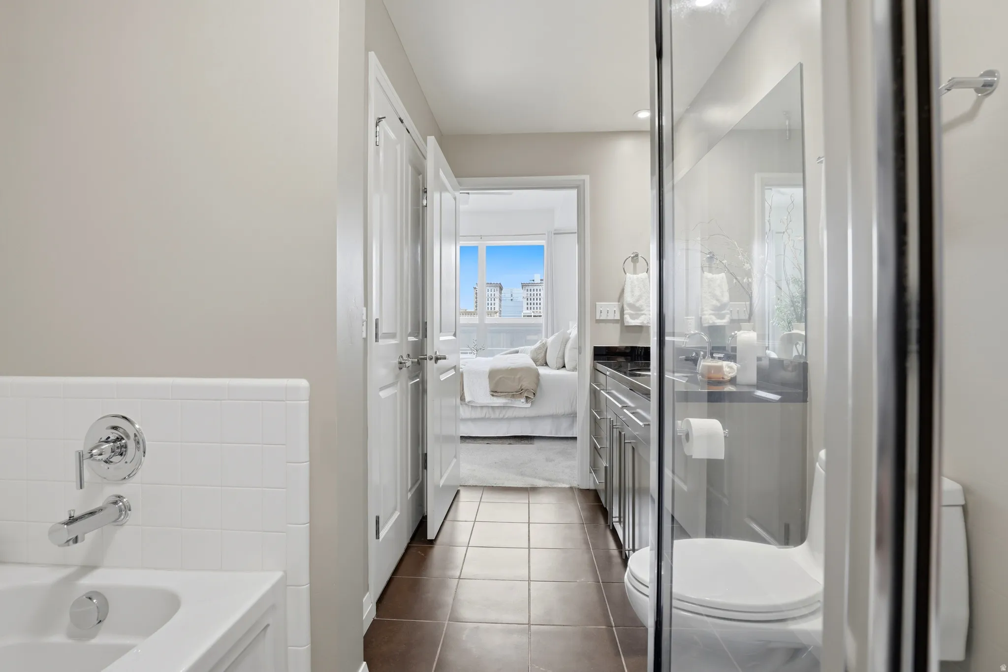 Bathroom featuring a white subway tile tub surround, chrome fixtures, dark-finish floor tiles, and a glass-enclosed shower