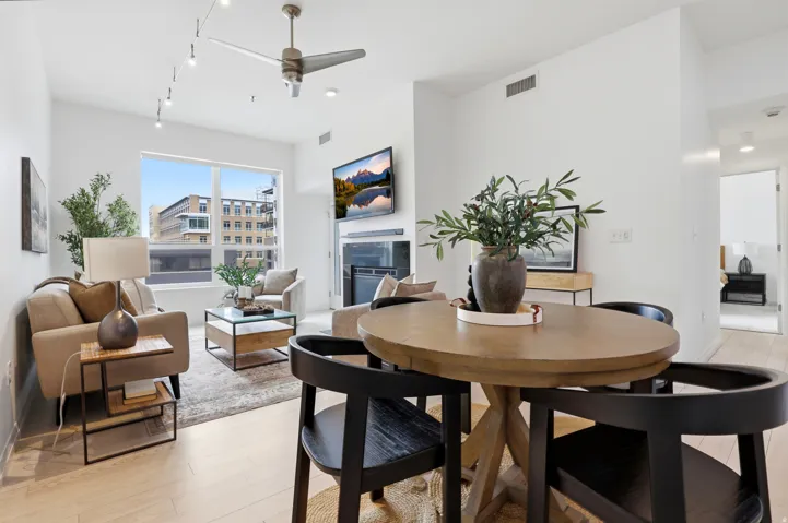 Open-concept living area with light wood-finish flooring, a contemporary ceiling fan, and track lighting