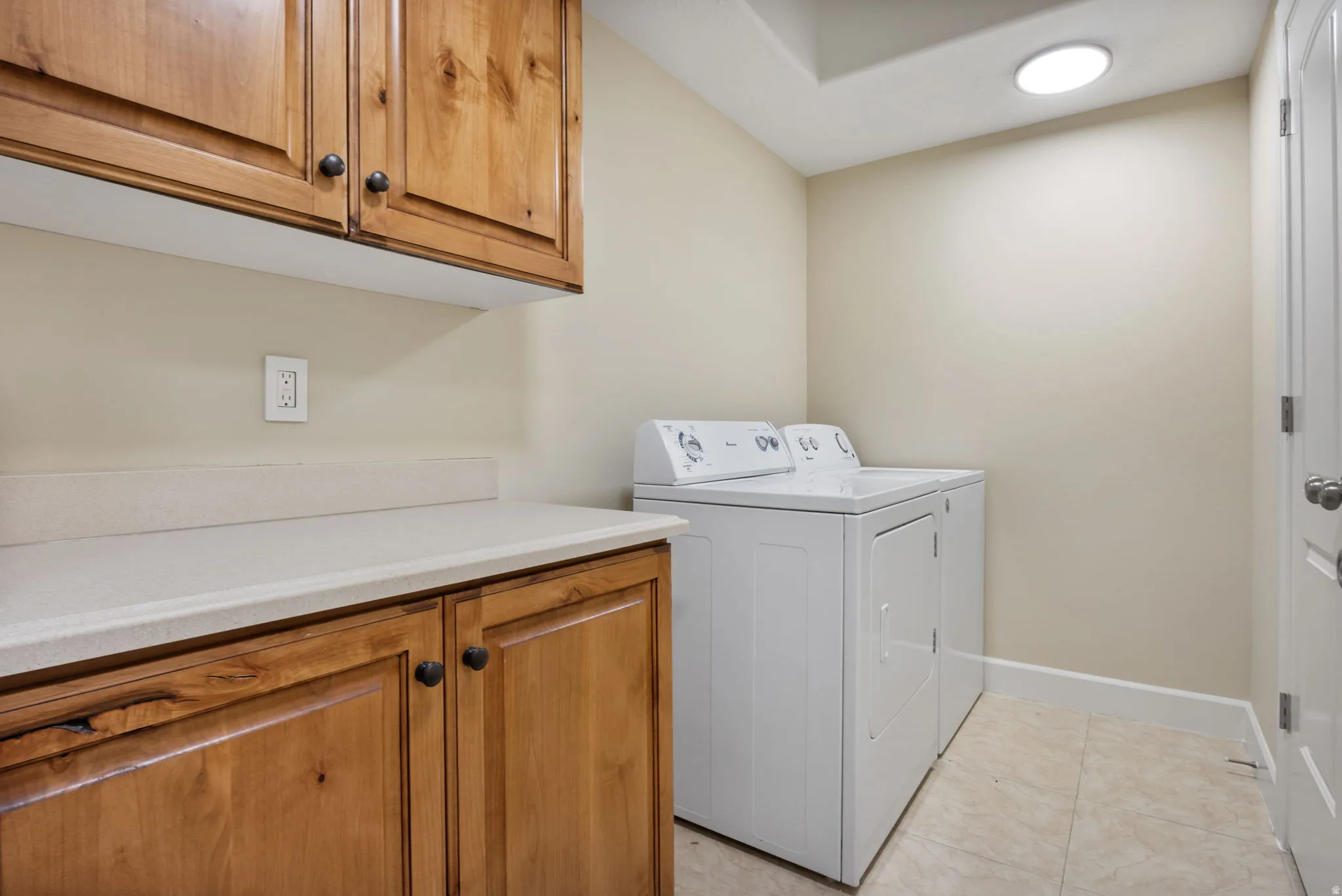 Utility room featuring light wood cabinetry, a light-toned countertop, and recessed ceiling lighting