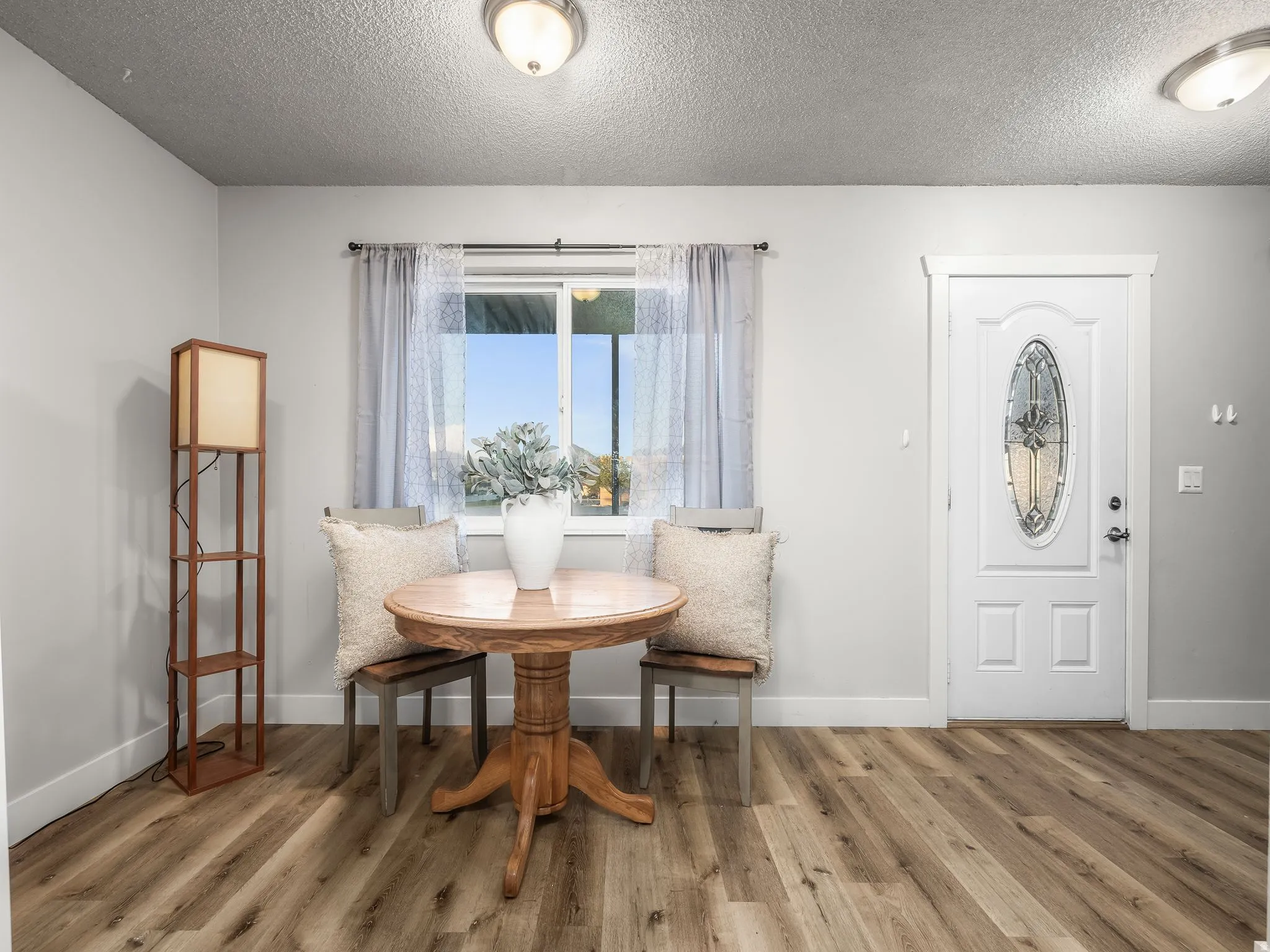 Entryway featuring wood-finish flooring, a white paneled door with an oval decorative glass insert, and neutral wall tones