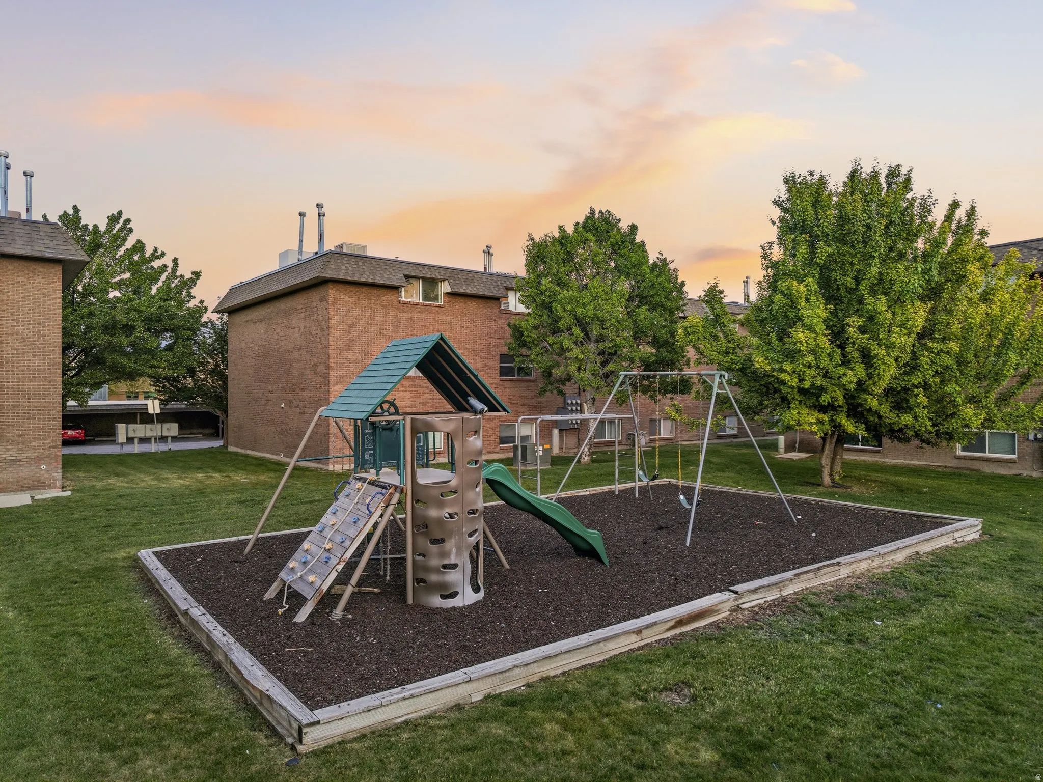 Outdoor playground featuring swings, a slide, and a climbing structure with wood chip surfacing