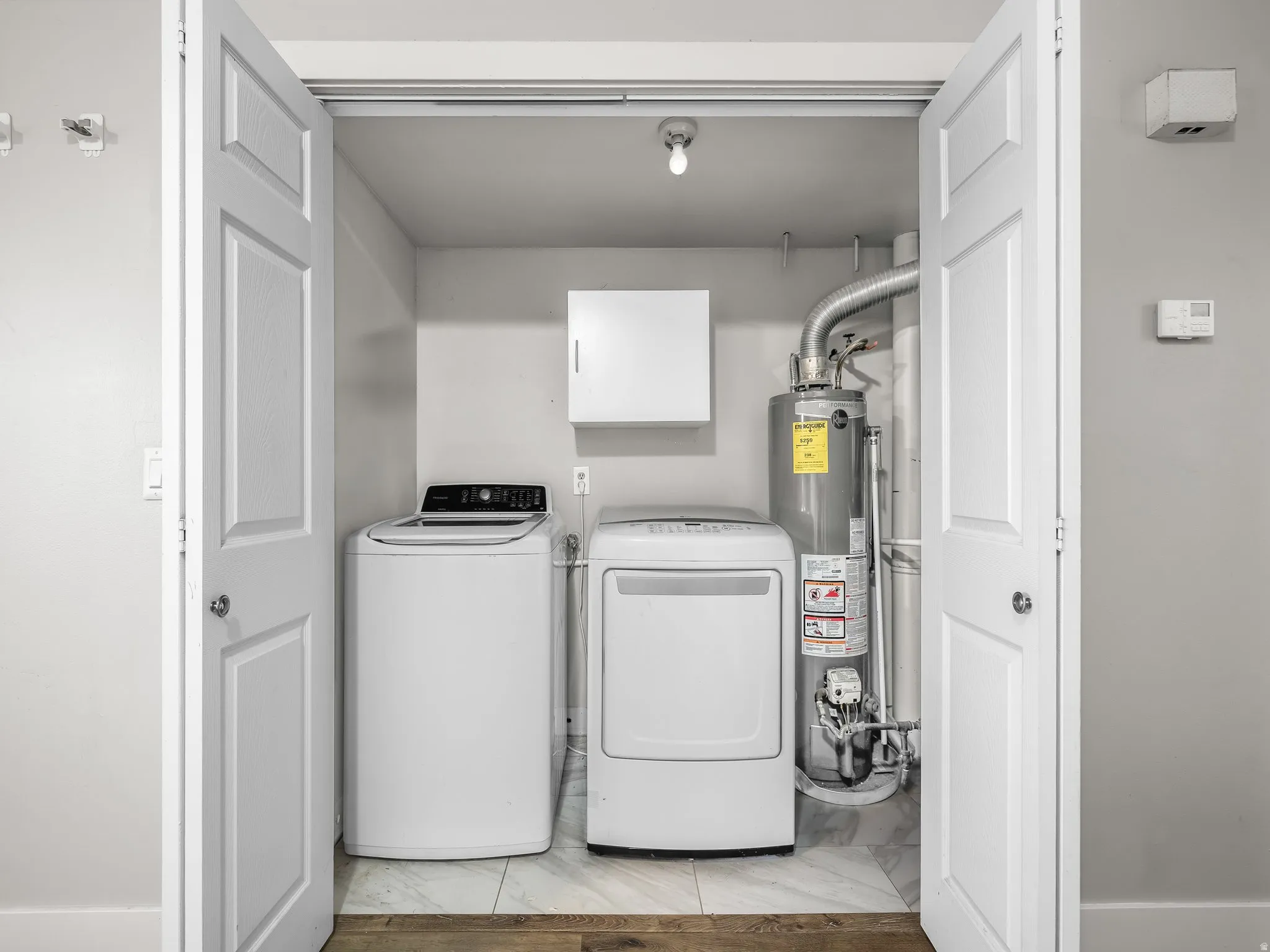 Dedicated laundry closet featuring a top-load washing machine, front-load dryer, and water heater