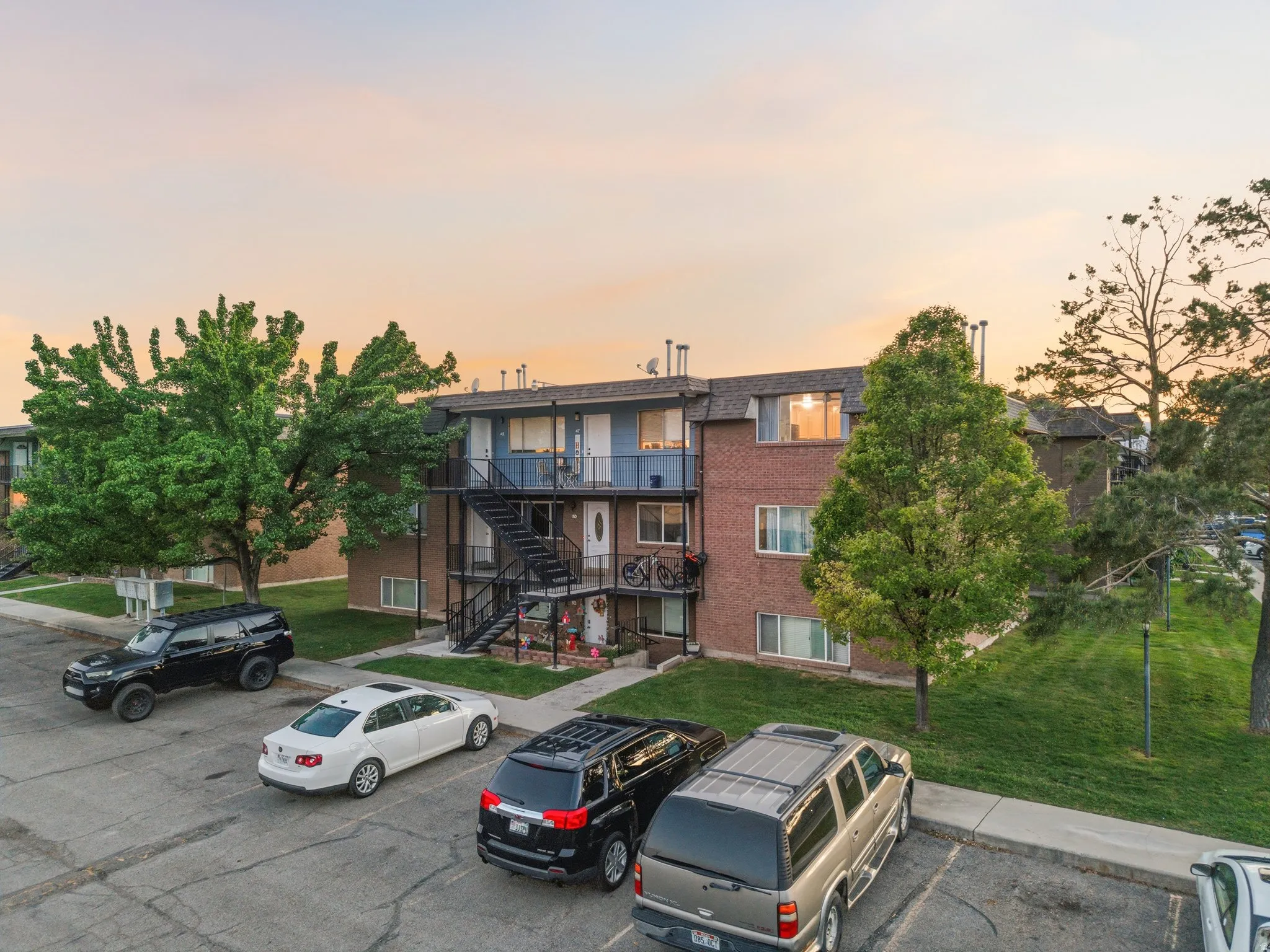 Multi-story residential building featuring brick and blue siding, individual balconies, and external metal staircases